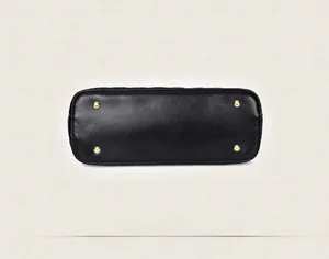 Detail view of large black handbag base featuring four gold protective metal rivets