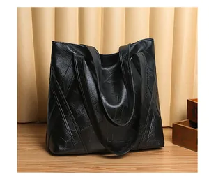 Close-up of black washed leather tote bag with geometric stitching on a wooden surface
