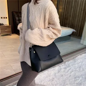 Minimalist black faux leather crossbody bag featuring a striped wide shoulder strap