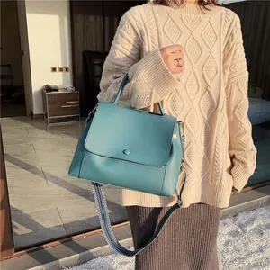 Elegant teal faux leather handbag with a stylish geometric woven wide shoulder strap
