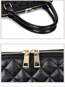 Detail of black quilted leather handbag with gold zippers and dual handles