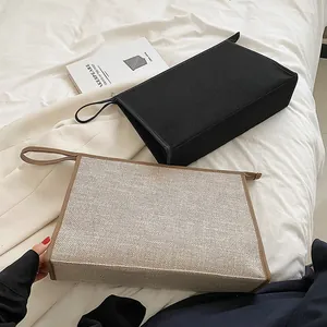 Detail of minimalist canvas briefcase set in beige and black with leather trim and zipper