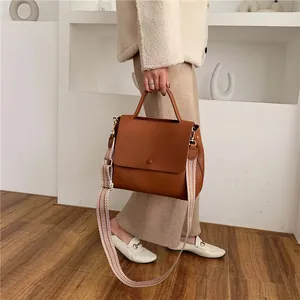 Brown faux leather crossbody handbag with geometric woven wide shoulder strap shown in 45-degree