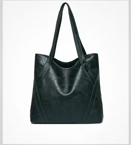 Detail of dark green tote bag featuring lychee texture and stitching on soft leather