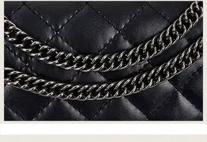 Close-up of black quilted leather with neat diamond stitching and silver chain detail