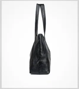 Close-up of a black washed leather tote bag showing textured panels and side strap detail