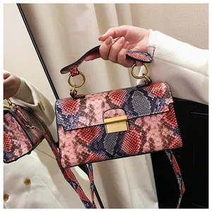 Detail of colorful snakeskin texture and gold metal ring handle on crossbody bag