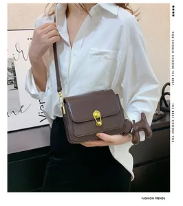 Detail of dark brown leather crossbody bag with gold buckle and a small horse charm