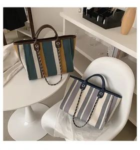 Detail of striped canvas bucket bags with faux leather handles and metal chain straps