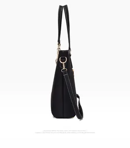 Detail view of black leather tote bag with contrast white stitching and gold hardware