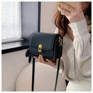 Detail of black leather crossbody bag featuring a vintage gold twist lock and silk scarf