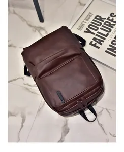 Detail view of the brown PU leather backpack texture and front zipper pocket on marble