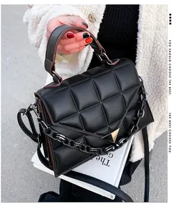 Detail of black quilted crossbody bag with golden triangle clasp and thick chain strap