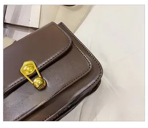 Detailed close-up of precise stitching and golden musical note lock on brown crossbody bag