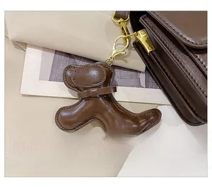 Detail of a dark brown leather dog-shaped charm with bow and golden lobster clasp