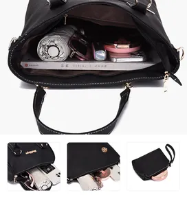 Detailed view of spacious black leather tote bag with interior storage and matching pouch