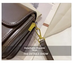 Detail showing the gold metal hardware and detachable strap on a dark brown bag