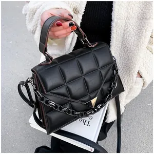 Close-up of black quilted leather handbag with gold triangle buckle and acrylic chain