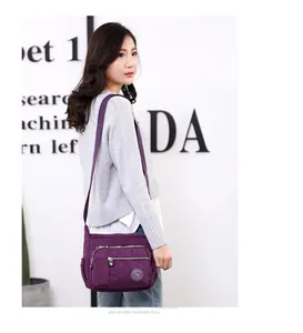 Detail view of purple nylon crossbody bag with multiple zip pockets and adjustable strap