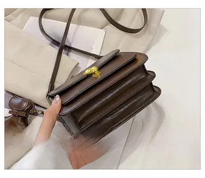 Detail of a brown leather crossbody bag with gold round twist lock and accordion layers
