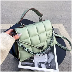 Detail of light green quilted crossbody bag with triangle metal buckle and chain strap