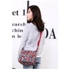 Side view of floral nylon crossbody bag featuring multiple zippers and adjustable strap