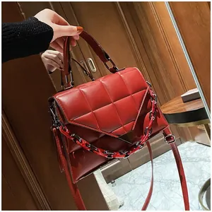 Close-up of red quilted leather handbag with decorative resin chain and metal buckle