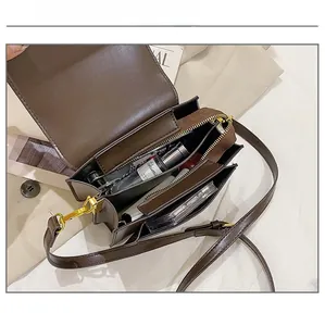Interior view of small brown crossbody bag showing compartments with makeup and perfume
