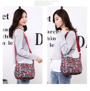 Detail view of colorful camo canvas crossbody bag with multi-layer zippers and red strap