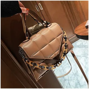 Brown quilted handbag with amber resin chain detail shown in a lifestyle indoor setting