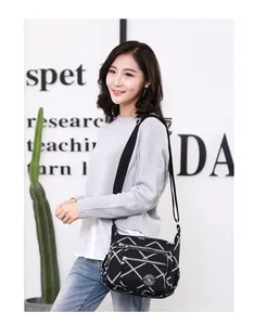 Detailed view of women's black multi-zipper canvas crossbody bag with white stripe patterns