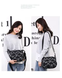 Detail of black nylon crossbody bag with geometric lines and multiple zip pockets