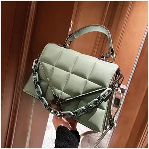 Close-up of mint green quilted leather handbag featuring metal triangle clasp and chain