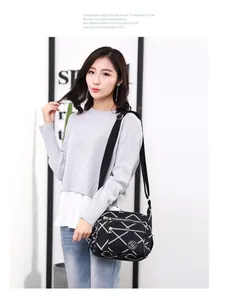 Close-up of black nylon crossbody bag with white geometric pattern and dual front zippers