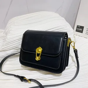 Minimalist black matte leather crossbody bag with unique gold safety pin metal buckle lock