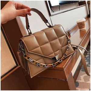 Detail of coffee brown quilted handbag with thick chain and silver triangle buckle
