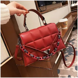 Macro view of dark red quilted leather handbag with chic chain and triangular metal lock