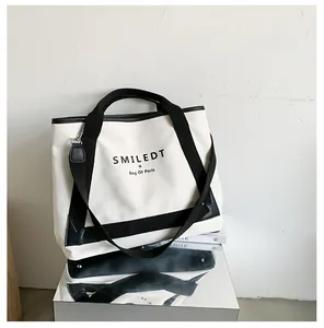 Détail du sac cabas en toile avec bordure noire et lettrage SMILEDT sur support miroir