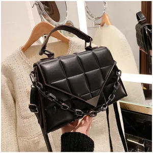 Detailed view of the black quilted crossbody bag with a metallic V-flap buckle and chain