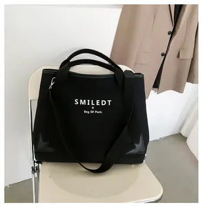 Détail d'un grand sac fourre-tout en toile noire avec texte blanc sur une chaise blanche