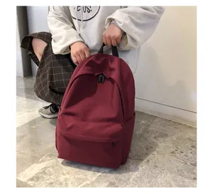 Detalle de mochila de nailon rojo oscuro con cremalleras y diseño de bolsillo frontal