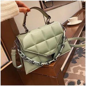Detail of light green quilted handbag with chain strap and triangle magnetic clasp