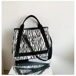 Détail du sac cabas en toile zébrée avec texte LIMITED et bandoulière noire