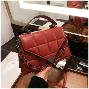 Detail of red quilted square handbag with resin chain and metallic triangle buckle
