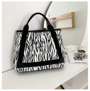 Détail du sac cabas en toile à motif zèbre avec poignées noires et logo Paris