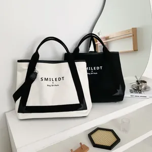 Détail du cabas en toile montrant l'imprimé logo et les coins renforcés en cuir
