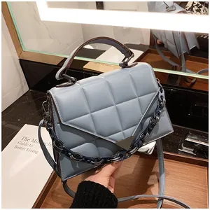 Detail view of light blue quilted handbag with metal buckle and chunky chain strap