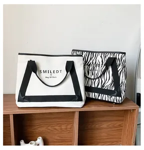 Détail de cabas en toile et imprimé zèbre sur étagère avec logo distinctif