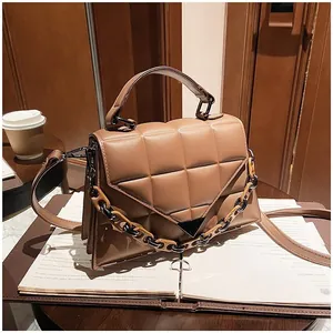 Detail of camel brown crossbody bag with diamond lattice texture and amber chain strap