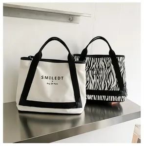 Vue détaillée de deux sacs cabas en toile avec motifs blanc et zèbre et poignées robustes